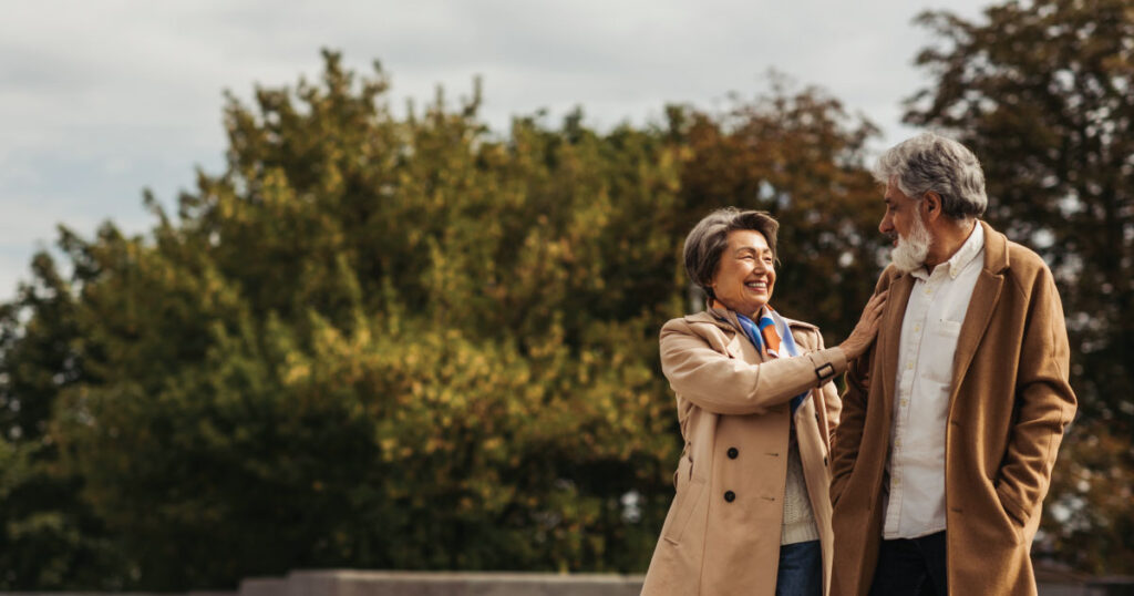Senior woman walking with husband through park.