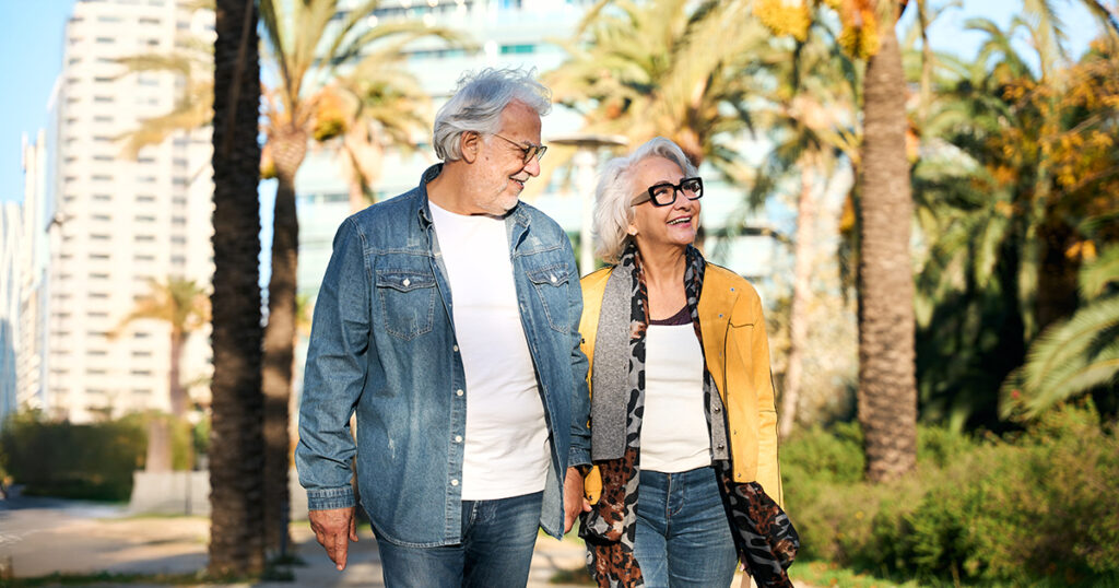Older couple walking with palm trees in the background