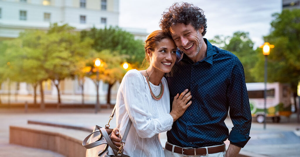 Happy married couple embracing and smiling while walking in a foreign city, representing U.S. expat married couples planning for the foreign earned income exclusion while living abroad