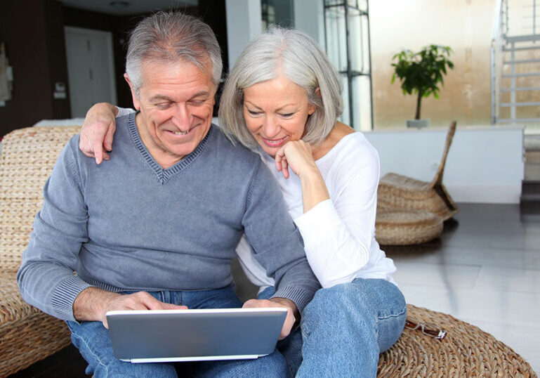 Couple sitting down and using a laptop.