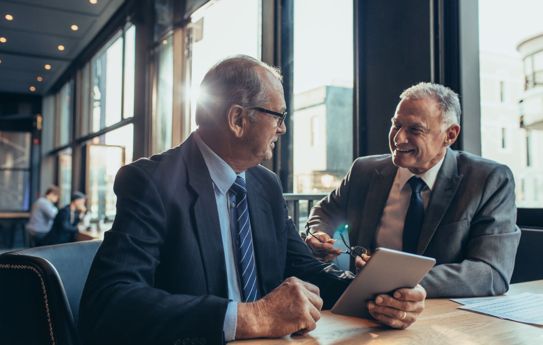 two men sitting at lunch with an ipad