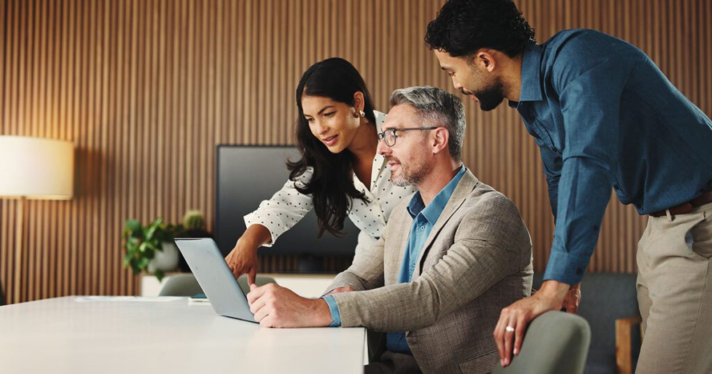 Strategic wealth advisors collaborating over a laptop to evaluate modern family office software solutions