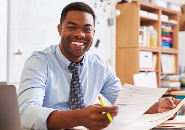 Portrait of African American male teacher working at desk
