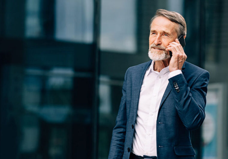 High-net-worth investor in a suit talking on the phone outside a modern office building, representing 2026 private market investing strategies for growth