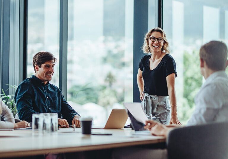 Group of professionals meeting around a conference table in a modern glass-walled boardroom, representing family office governance models and structured decision-making for multigenerational wealth
