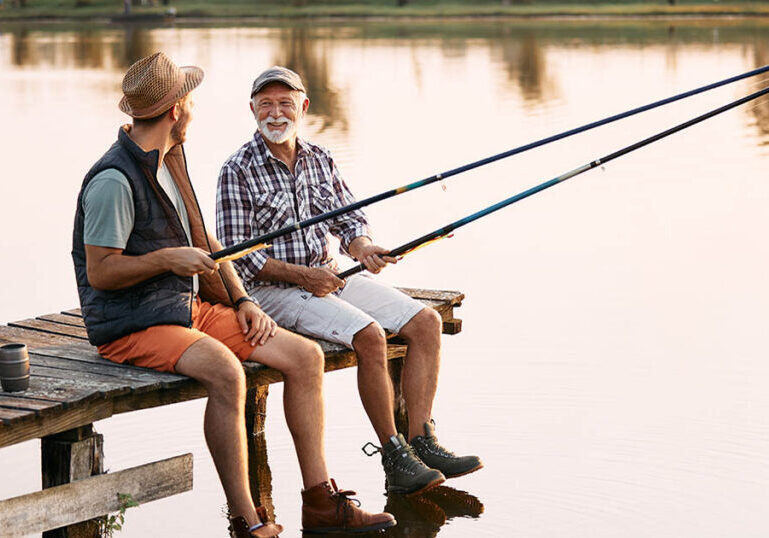 Happy senior man with no retirement regrets fishes with his son