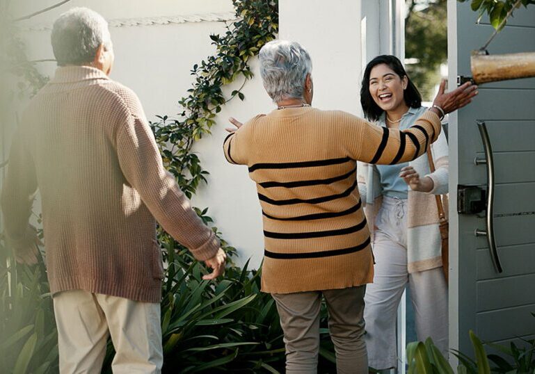 Older parents warmly greeting their adult daughter at the front door, symbolizing family support and the importance of setting healthy boundaries when financially helping grown children.