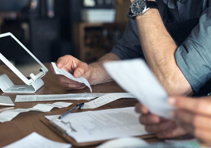 Couple reviewing receipts and logging on laptop